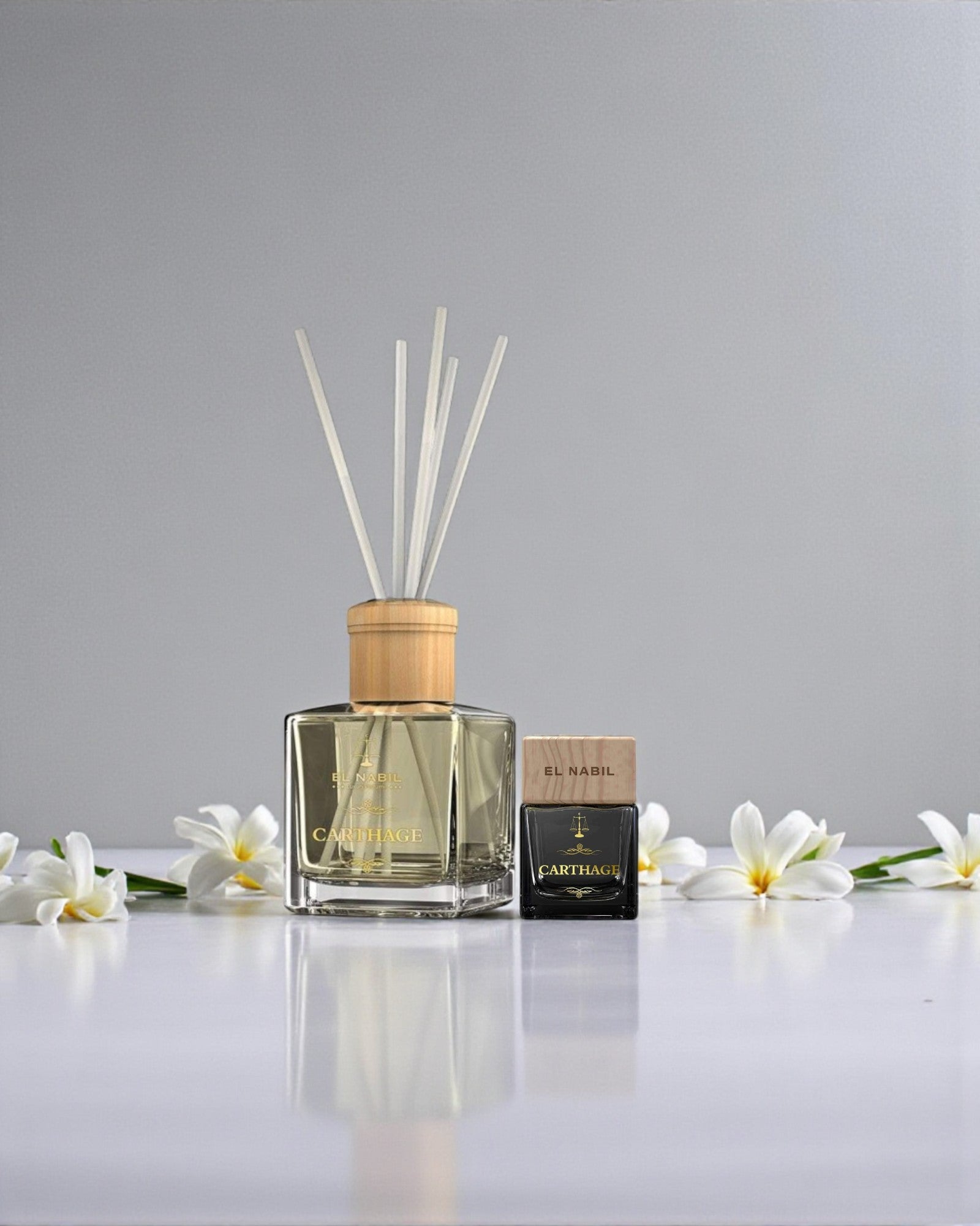 Pack Carthage El Nabil – diffuseur en roseaux 150 ml et dressing perfume 50 ml, fleurs blanches autour, ambiance florale jasmin sur fond clair.