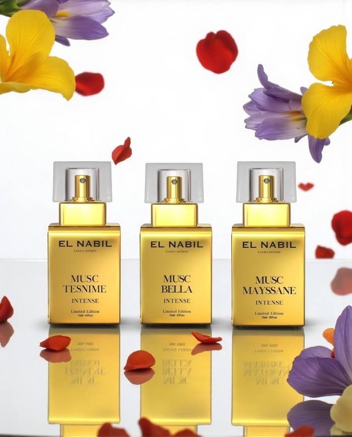 Lot 3 Eaux de Parfum Intense El Nabil 15 ml – Musc Bella, Musc Mayssane, Musc Tesnime, flacons or alignés avec pétales et fleurs colorées, reflet sur surface brillante.