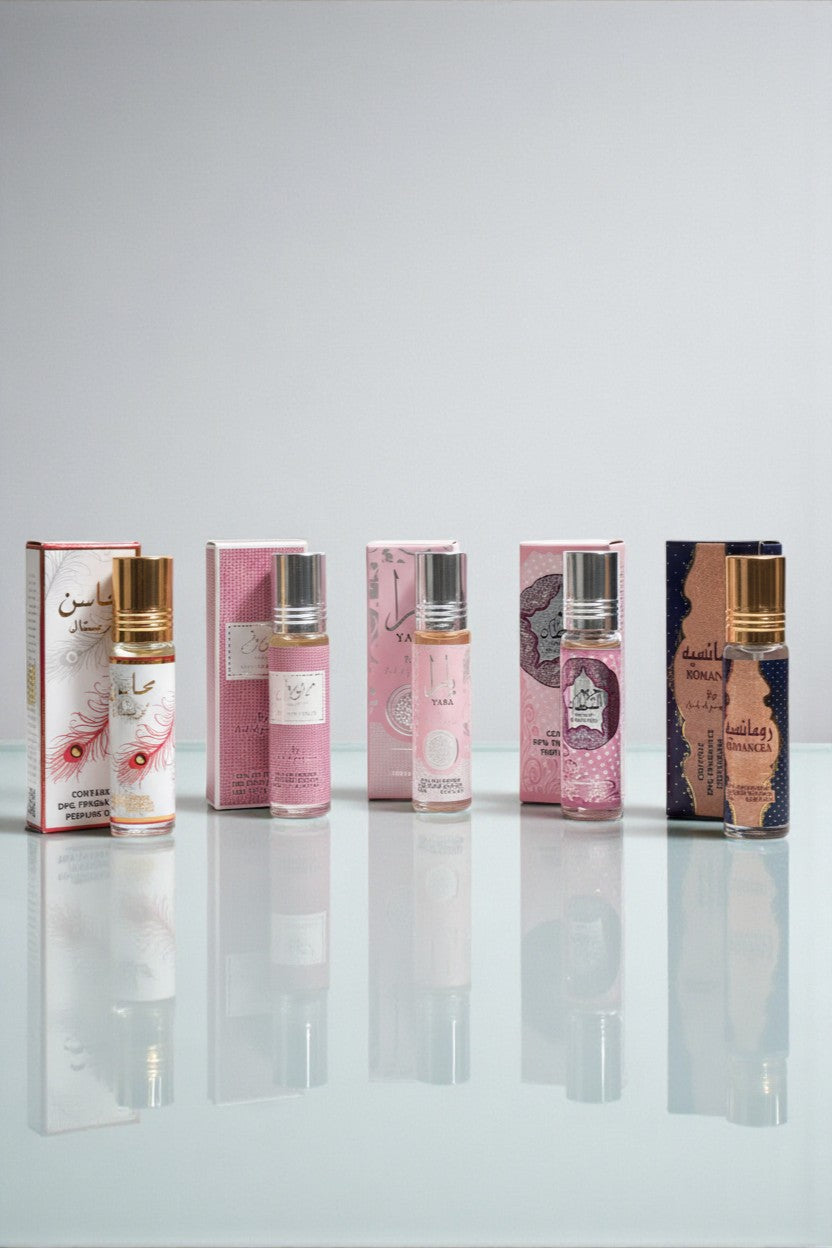 Pack 5 roll-on sans alcool Ard Al Zaafaran 10 ml – Mahasin Crystal, Mousuf Wardi, Yara, Hareem Al Sultan, Romancea, flacons alignés devant leurs étuis roses, reflet sur surface brillante.